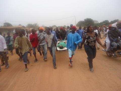 angry relatives and friends carrying the body of one of those killed